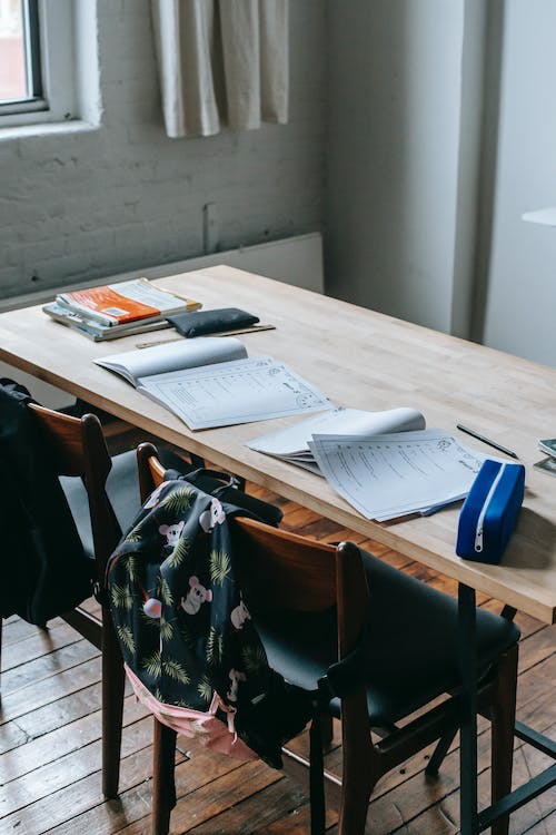 wooden school desk with homework and backpacks